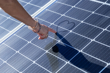 Hand drawing a heart on a solar panel.