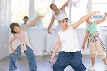 Obraz premium Portrait of happy teen boy training modern street hip-hop during group dance lesson in modern sports room