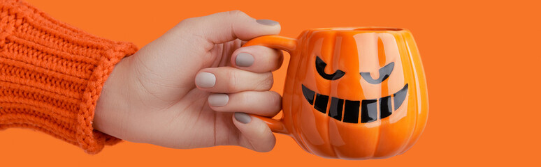 Cappuccino latte coffee in pumpkin cup on orange background. Halloween celebration concept