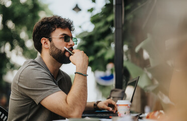 Businessman working with a laptop, deep in thought while holding a pen. Professional setting...