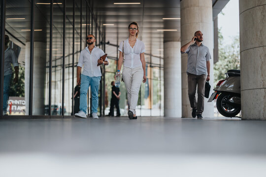 Group of businesspeople in professional attire walking and talking in an urban downtown area on a sunny day.