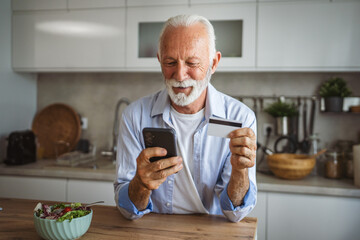 senior man buy online on mobile phone and use credit card at home