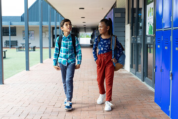 Biracial boy and girl walk past lockers at school