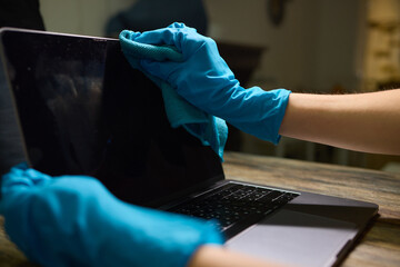 Person Cleaning Laptop Keyboard with Gloves and Cloth, Taking Precautions for Health and Hygiene