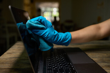 Person Cleaning Laptop Keyboard with Gloves and Cloth, Taking Precautions for Health and Hygiene