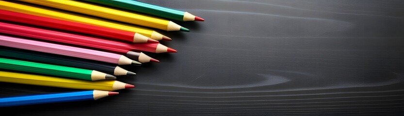 Fototapeta premium Top view of crayons and pencils on black wooden table for back to school designs concept with copy space.