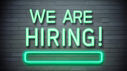 Fototapeta premium We Are Hiring Neon Green Sign on Dark Brick Wall - Perfect for Modern HR Recruitment Campaigns