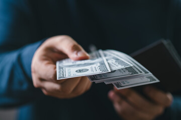 Close-up of a person handing over US dollar bills. Concept of payment, transaction, finance,...