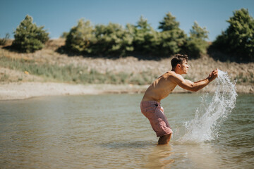 Fototapeta premium Man enjoying a sunny day at the lake, splashing water and having fun in nature.
