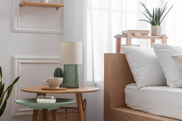 Stylish living room interior with bed, bedside tables, lamp and houseplants
