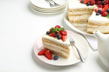 Tasty sponge cake with fresh berries and mint served on white table, space for text