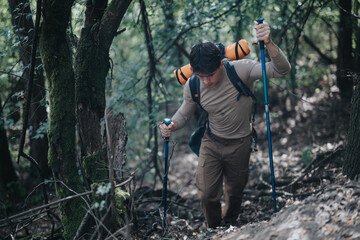 Man hiking through a dense forest with trekking poles and a backpack, enjoying the adventure of outdoor activities in nature.