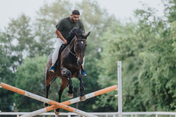 Male rider on a horse jumping over a hurdle at an equestrian event outdoors, showcasing skill and teamwork.