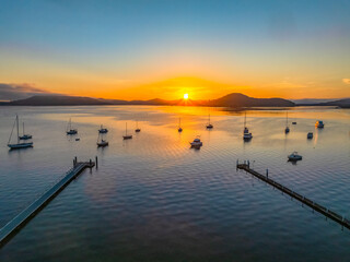Sunrise over the calm water with boats and reflections