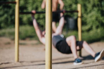 Obraz premium A man working out on outdoor fitness equipment in a park, emphasizing strength training and active lifestyle
