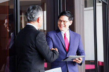 Smiling businessmen join hands in business investment.