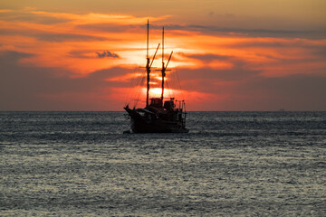 Obraz premium Cruise ship on the sea with sunset over the horizon line