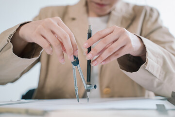 In her office, the professional woman architect meticulously uses a compass in hand to refine the...