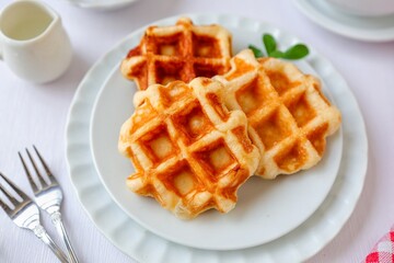 Waffles in white plate on white background with fork