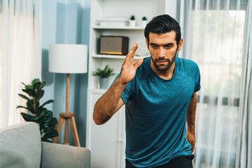 Athletic and sporty man running posture at home body workout exercise session for fit physique and healthy sport lifestyle at home. Gaiety home exercise workout training.