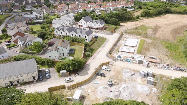 Drone view of new homes being built in a residential setting in Bude, Cornwall, United Kingdom, illustrating the construction progress amidst an organized suburban landscape