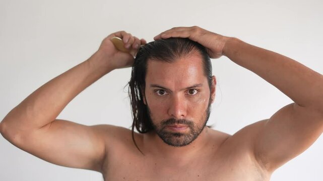 handsome, long-haired Latino man, in the bathroom, combing his hair