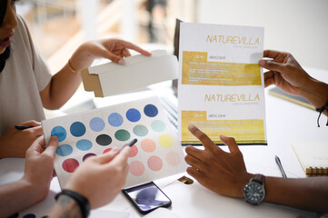 Business people, hands and color palette with swatches for planning, discussion or design at office. Closeup of employees discussing shades or ideas for skincare pamphlet or brochure at workplace