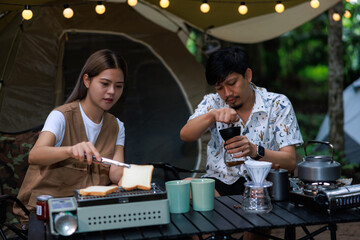 adventurous young couple at their campsite, is preparing toast and coffee for their breakfast.