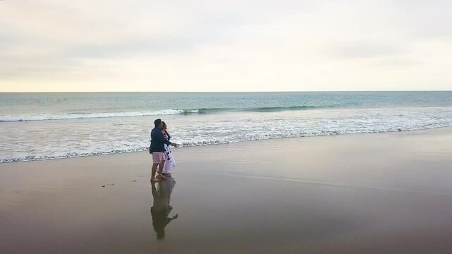aerial shot of couple walking and holding hands on the coast, windy 2.7K