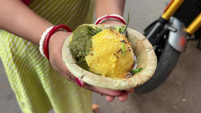 Indian Gujarati traditional Dish Green Peas Dhokhla held by an Indian girl.