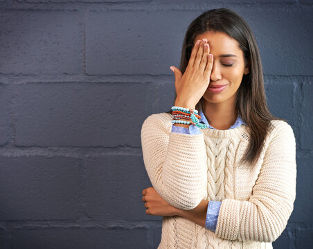 Woman, smile and hand on face with forget information, thinking and stupid emoji by brick wall mockup. Female person, happy and remember with embarrassing memory, space and oops by dark background