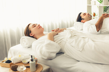 Obraz premium Caucasian couple customer enjoying relaxing anti-stress spa massage and pampering with beauty skin recreation leisure in day light ambient salon spa at luxury resort or hotel. Quiescent