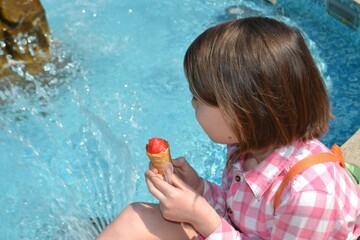 Close up image of girl hand holding fresh waffle cone with vanilla and raspberry ice cream on the...