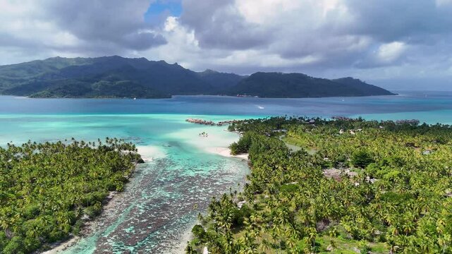 Azure south pacific ocean water surrounds a motu near the tropical island of Taha'a in French Polynesia. Aerial view captured by drone