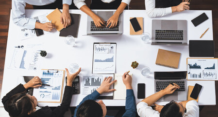 Obraz premium Top view analyst team utilizing BI Fintech to analyze financial data at table in meeting room. Analytic BI dashboard power on paper for business insight and strategic marketing planning. Prudent