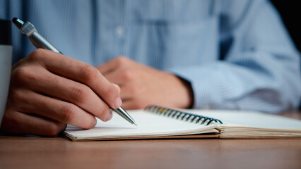 Male hand taking notes on the notepad. businessman working at work table, checklist writing planning investigate enthusiastic concept. focus on man hand holding pen, putting signature at official pape