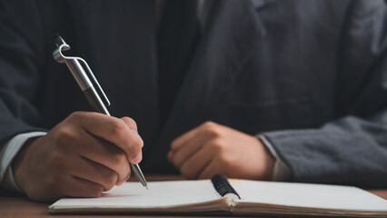 Male hand taking notes on the notepad. businessman working at work table, checklist writing...