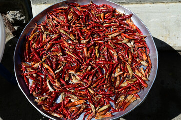 Fototapeta premium Closeup of Many of Fresh Red chilies peppers on a silver tray placed outside the building in the sun to dry. For use in cooking at Thailand.