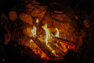 Campfire. Blazing logs burning in the stone-enclosed fireplace. Night shot