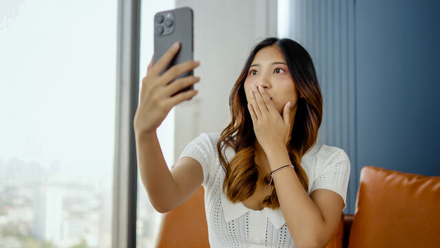 Shell-shocked young woman covers mouth with hands in dismay over mistake. secret worried expression when video call talking to a friend or lover on the phone, Try to cover it up so that nothing happen