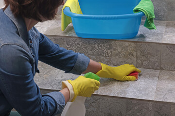 Woman in rubber gloves washes tile staircase in house. Cleaning and cleanliness, detergents. 