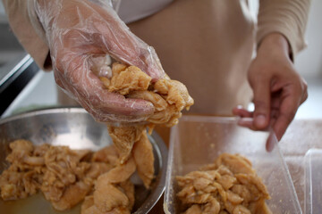 Close up of a person hand marinating chicken meat in metal bowl