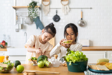 Two young asian girls preparing healthy meal together in modern kitchen, engaged in their culinary activity teamwork and joy of cooking with fresh vegetables healthy and nutritious nature of meal