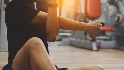 Man in black sportswear stretching arms with cross-body shoulder stretch pose and warming up before weight training in fitness gym. healthy sports lifestyle builds muscle, health and fitness concept.