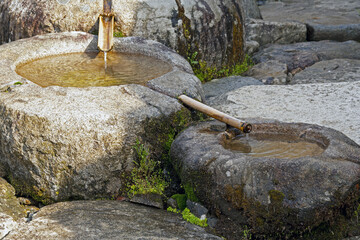 Seungju-eup, Suncheon-si, South Korea - April 9, 2011: Morning view of mineral spring water flowing through two bamboo pipes and two stone mortars at backyard of Seonamsa Temple
