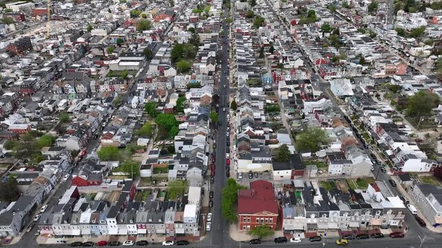 Traffic of main street in american town during cloudy day. Different pattern of homes and rooftops. Housing area during sunny day in small historic town. Aerial top down backwards shot.