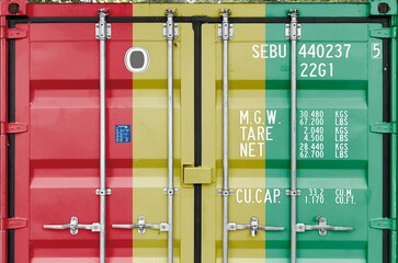 Guinea flag depicted on metal doors of shipping cargo container outdoors in docks area close up