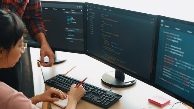 Back end or software developer manager supervising his team on new application program development on debugging and solving complex code algorithms on monitor. Burgeoning