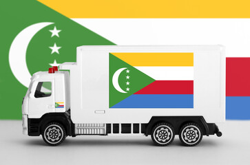 Comoros flag depicted on side wall of white delivery van close up. Shipping and local delivery concept