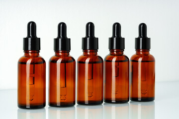 Row of various brown glass dropper bottles isolated on white background